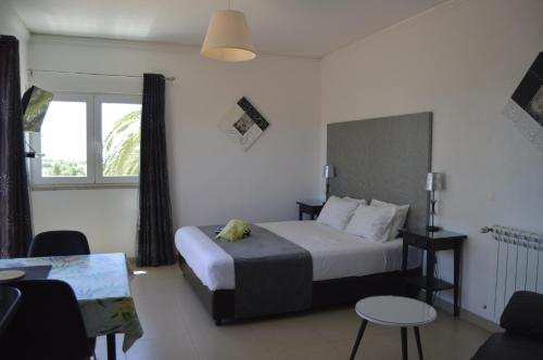 a bedroom with a bed and a table and a window at Tavira Vacations Apartments in Tavira