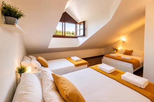 a attic room with three beds and a window at Chalet Bilbao-Aeropuerto in Sondika