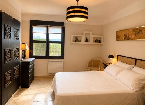 a bedroom with a large white bed and a window at La Tuiliere in Oraison