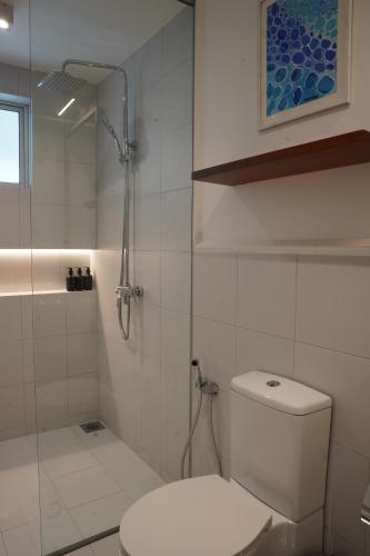 a white bathroom with a shower and a toilet at Eklektik in Colombo