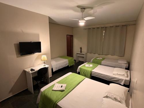 a hotel room with three beds and a television at Hotel Elithi - O melhor custo benefício in Itapeva