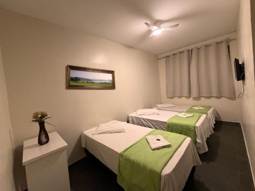 a room with two beds and a picture on the wall at Hotel Elithi - O melhor custo benefício in Itapeva