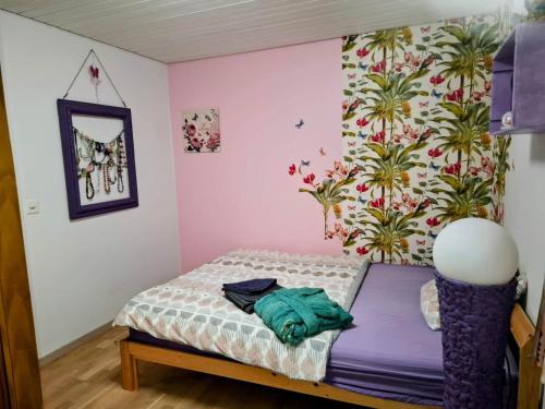 a small bed in a room with a flower wall at Maison mitoyenne avec terrasse in Asuel