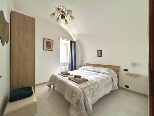 a white bedroom with a bed and a chandelier at La Minicasa in Pacentro