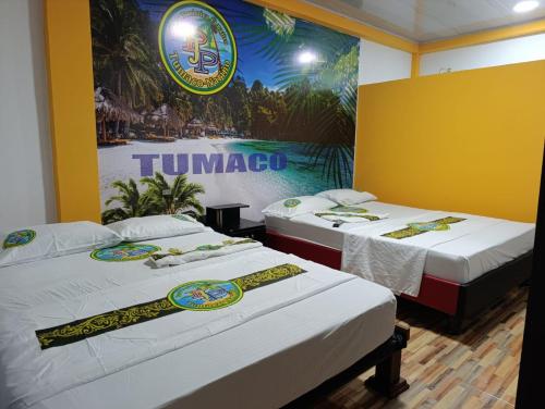 two beds in a room with a sign on the wall at Hotel Pablo's in Tumaco