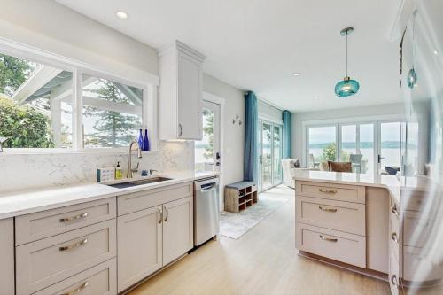 a large kitchen with white cabinets and windows at Breezy Point Retreat in Saratoga Shores