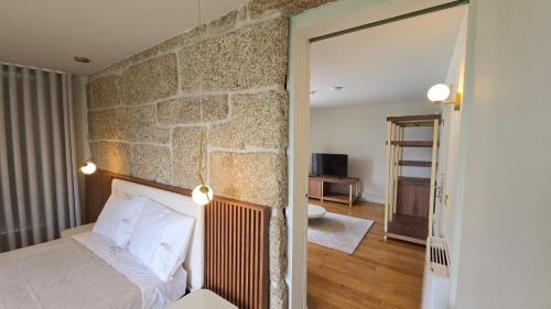 a bedroom with a stone wall with a bed and a mirror at Caza de Cima de Villa in Penafiel