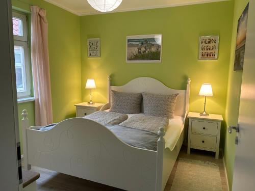 a bedroom with a white bed with green walls at Familienhaus Stadtmitte in Neustrelitz