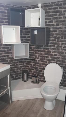 a bathroom with a white toilet and a brick wall at Maison Conviviale amiens in Amiens