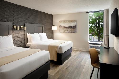 a hotel room with two beds and a desk and a window at Hotel Arlington in Arlington
