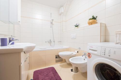 a bathroom with a toilet sink and a washing machine at Sea & Sky Retreat in Makarska