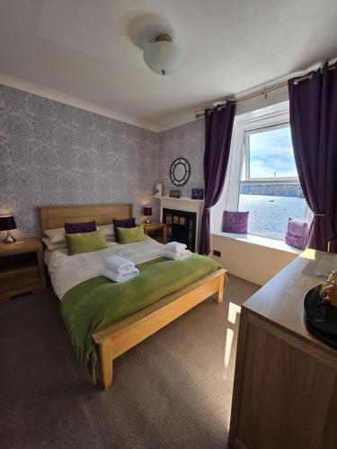 a bedroom with a bed and a window with the ocean at Mishnish Hotel in Tobermory