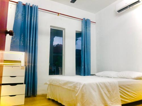 a bedroom with blue curtains and a bed and a dresser at Rumah Teduh Desa in Kuala Rompin