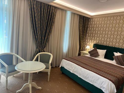 a hotel room with a bed and a table and chairs at Savoy Hotel in Chişinău