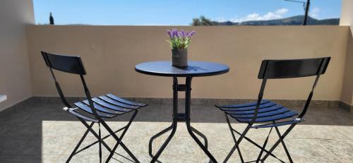a table with two chairs and a table with purple flowers on it at Ze Di Ma House in Kythira