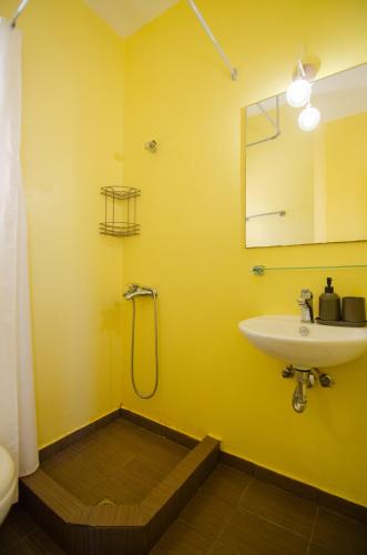 a yellow bathroom with a sink and a mirror at Mylopota Studio I in Mylopotas