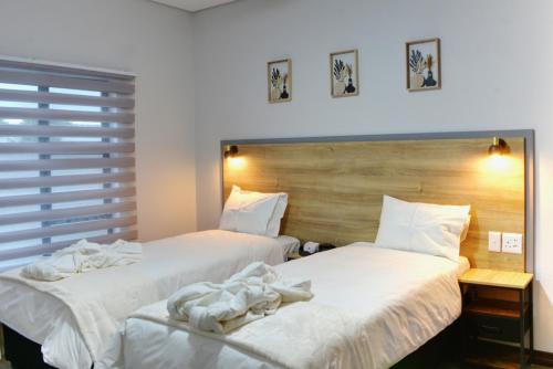 two beds in a hotel room with white sheets at Solana Villa in Hazyview