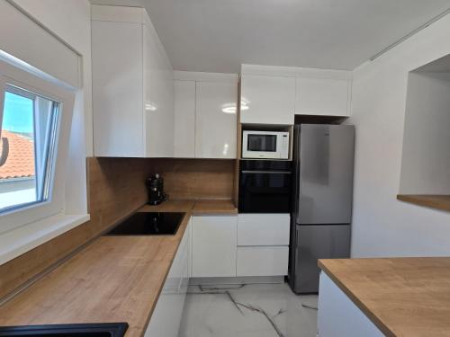 a kitchen with white cabinets and a black refrigerator at Braavos apartments Šibenik Deluxe near Marina in Šibenik