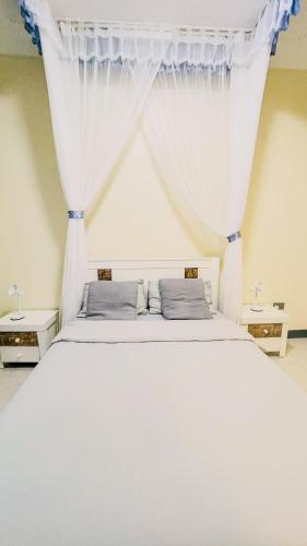 a bedroom with a white bed with curtains at Bwebajja Hub in Bwebajja