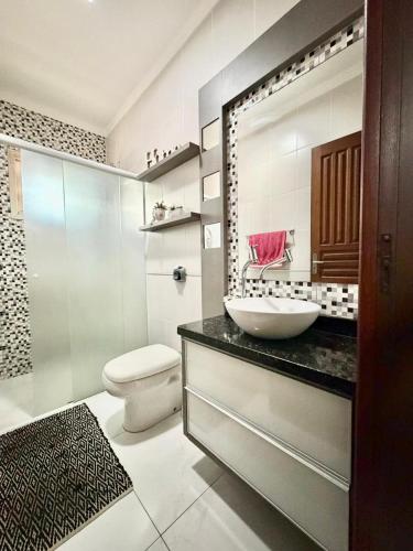 a bathroom with a sink and a toilet and a mirror at Quarto 3E Joinville Costa e Silva perto Centro in Joinville
