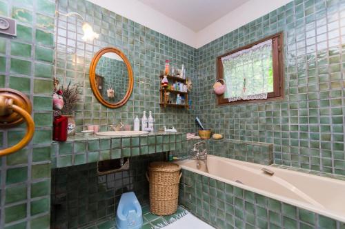 a green tiled bathroom with a tub and a sink at Gite de Loche in Quet-en-Beaumont