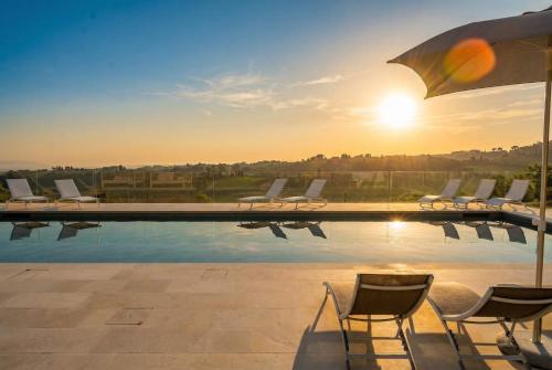 a swimming pool with chairs and the sun setting at VILLA OXA 12&2, Emma Villas in Imola