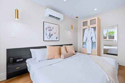 a white bedroom with a large bed and a closet at Casa Hotels Gerrard Modern Downtown Suite in Toronto