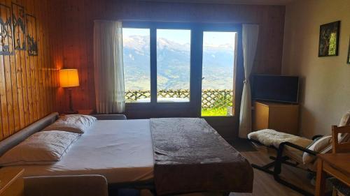 a bedroom with a bed and a large window at Studio Bellevue Veysonnaz in Veysonnaz