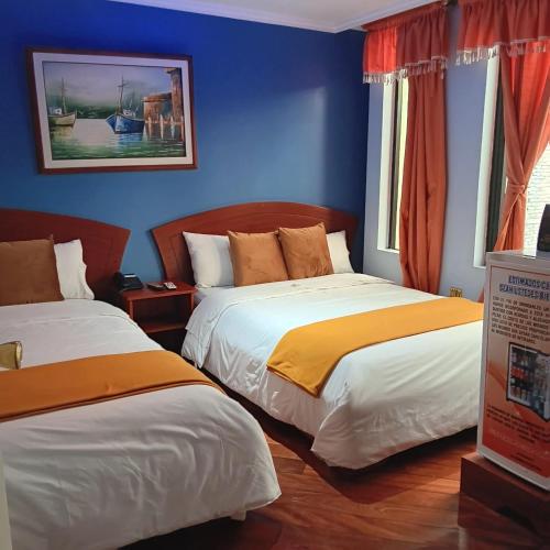 two beds in a room with blue walls at HOTEL MADURAI in Ambato