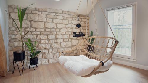 a swinging chair in a room with a stone wall at Maisons Vaudésir - Rose, Chablis in Chablis