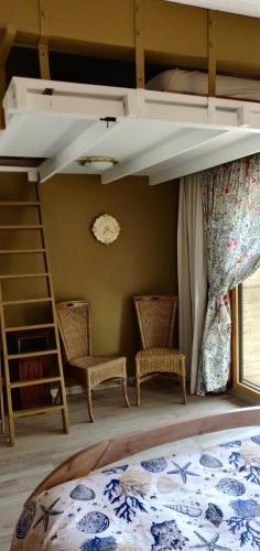 a bedroom with a bunk bed with two chairs at Le nid bucolique in Publier