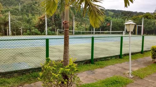 a tennis court with a palm tree next to a fence at Apartamento Hotel Cavalinho Branco in Águas de Lindóia