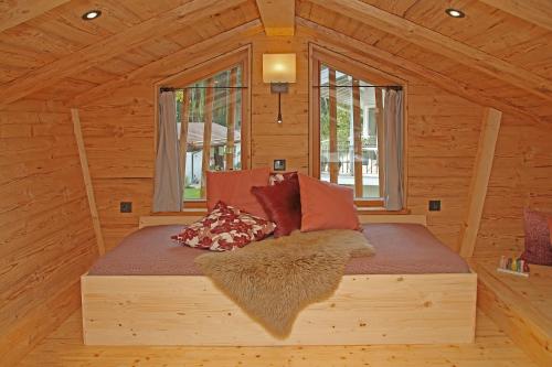 a bed in a wooden cabin with pillows on it at Das Alm-Chalet-Chiemsee in Bernau am Chiemsee