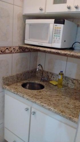 a kitchen counter with a sink and a microwave at Apartamento Hotel Cavalinho Branco in Águas de Lindoia