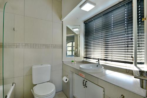 a bathroom with a toilet and a sink and a window at Caribbean Estates by MyResorts in Port Edward