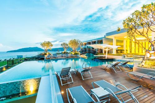 a hotel with a swimming pool and chairs on a deck at Crest Resort & Pool Villas in Patong Beach