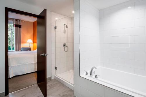a bathroom with a tub and a shower with a bed at Four Points by Sheraton Grande Prairie in Grande Prairie