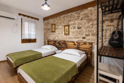 two beds in a room with a brick wall at Kitarat Berat Castle in Berat