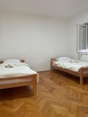 two beds in a room with wooden floors at DAS Apartmani Bileća in Bileća