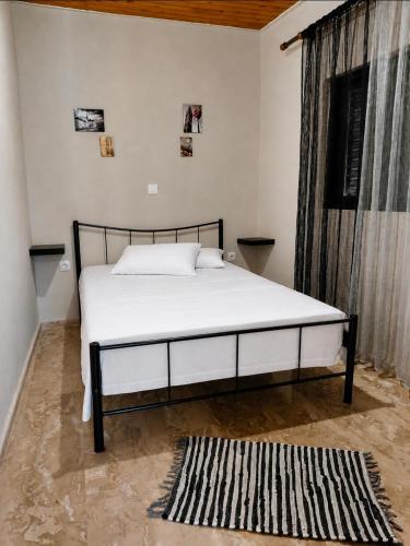 a white bed in a room with a window at Pefanis House in Preveza