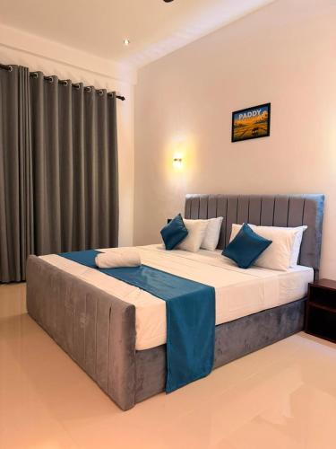 a bedroom with a large bed with blue pillows at Cozy Bay Hotel in Arugam Bay