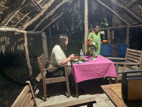 two people sitting at a table in a hut at Fireworks Tree House in White Sands