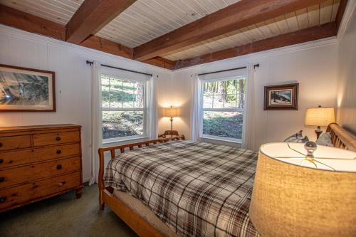 a bedroom with a bed and a dresser and two windows at Hillhouse By Hauserman Rentals in Homewood