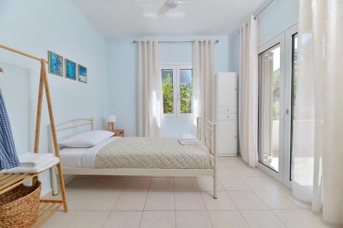 a white bedroom with a bed and a window at Vottas Seaside House Nea Makri in Nea Makri