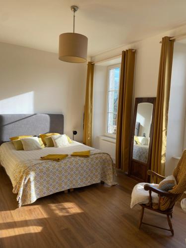 a bedroom with a bed and a mirror and a chair at La Maison du Hommeel in Gratot