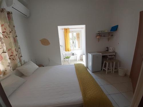 a bedroom with a white bed and a window at Kampos Rooms in Palaiochora