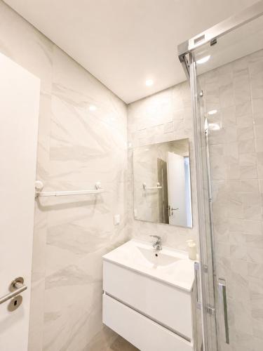 a white bathroom with a sink and a mirror at Casa do Leme in Nazaré