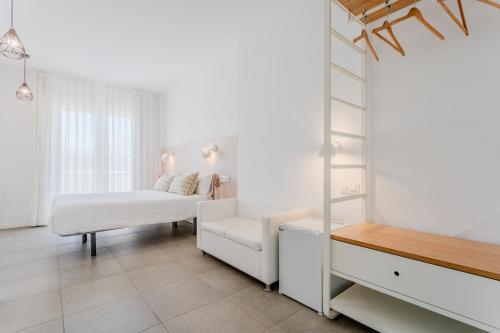 a white room with a bed and a chair at Hostal La Isla in Carboneras