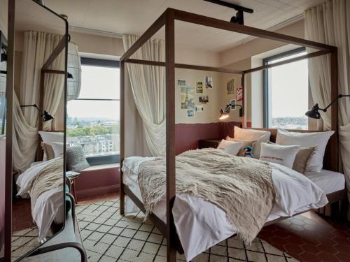 a bedroom with a canopy bed and a large window at 25hours Hotel Das Tour in Düsseldorf