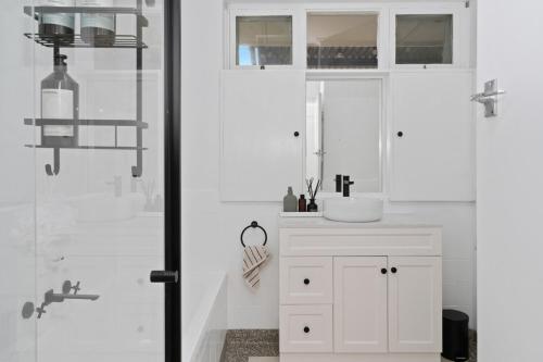a white bathroom with a sink and a shower at Oak and Olive - Glenelg in Glenelg
